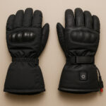 冬のバイク向けにデザインされた黒いウィンターグローブが置かれているシンプルな構図。背景は落ち着いたベージュで、グローブの質感や防寒性能がわかるように丁寧に描写されている。