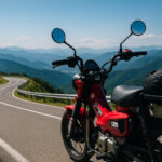 山岳地帯のワインディングロードのカーブ沿いに停められた赤いホンダCT125を写した写真風の画像。遠くに重なる青い山並みと澄んだ空が広がり、ツーリングの爽快感を感じさせる構図。