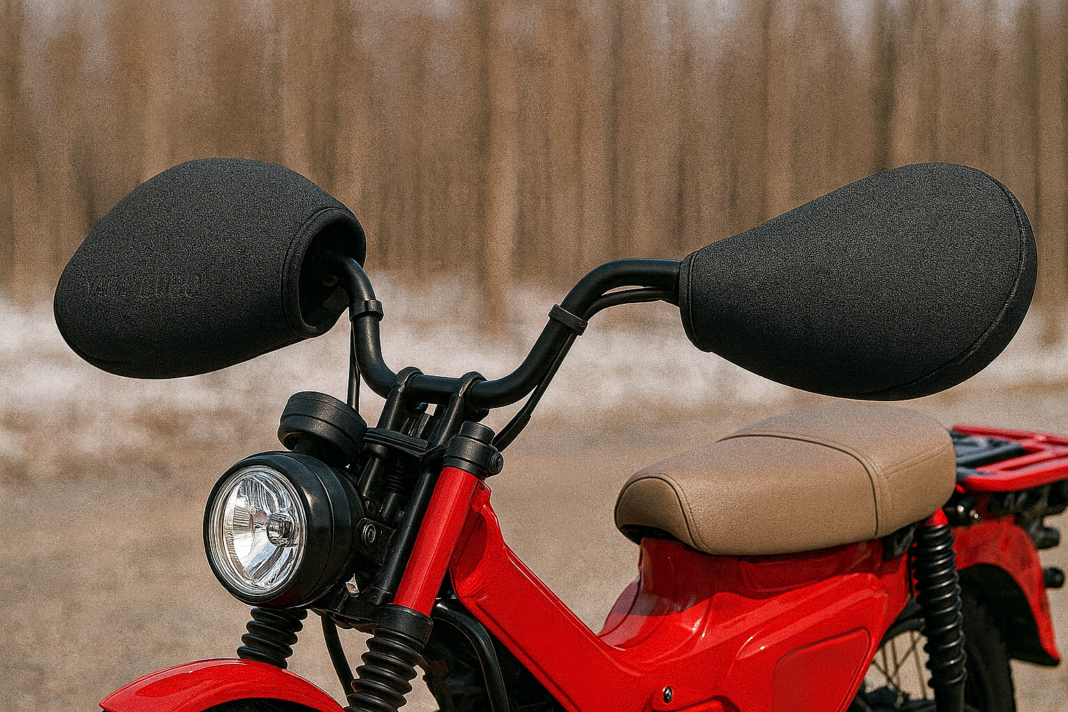 冬の屋外で赤い小型オフロードバイクのハンドル周りをクローズアップした写真風イメージ。黒いハンドルカバーが左右に装着され、背景には雪の残る林がぼんやりと広がっている。バイクの車体にはブランド名やロゴが一切なく、無地のデザインとして描かれている。