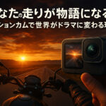 「夕焼けの中をバイクで走るライダーの視点と、手前に掲げられたアクションカメラが同じ景色を映し出している構図。『あなたの走りが物語になる。アクションカムで世界がドラマに変わる理由』というタイトルが夕空に重ねて描かれた、ツーリングの臨場感と映像表現の魅力を伝えるアイキャッチ画像。」